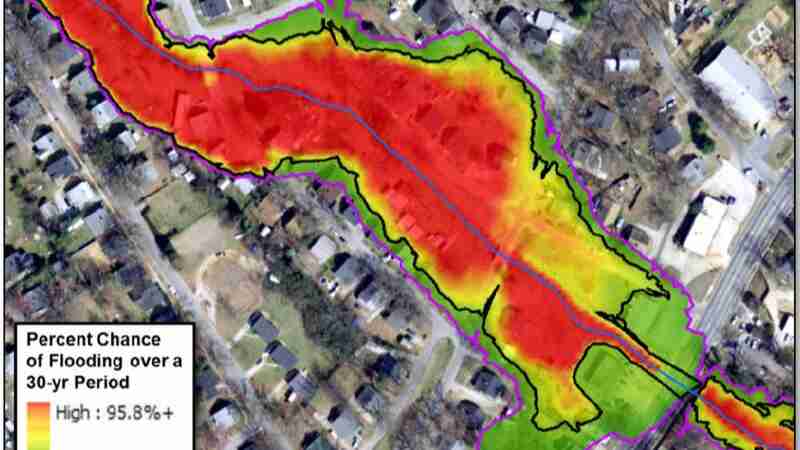 Computer generated flood analysis shows chance of flooding over a 30-year period overlaid on aerial photo of a city. A wide area of reds and oranges shading upstream of an encroachment of the valley i..., tags: schätzungen - CC BY-SA